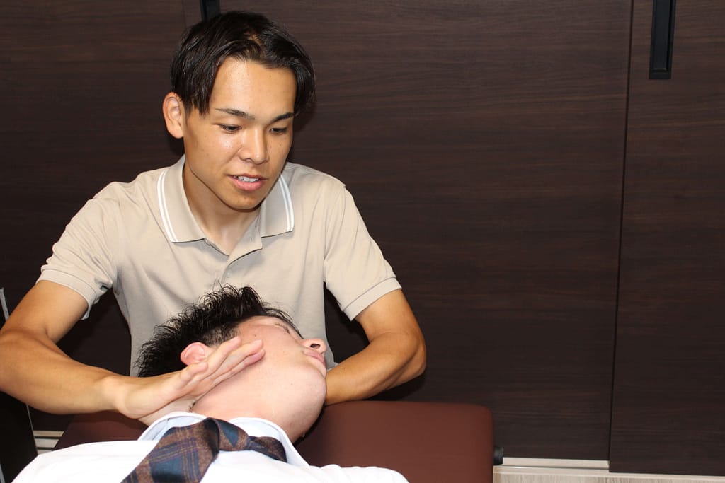 男性従業員の頸を矯正している院長の写真