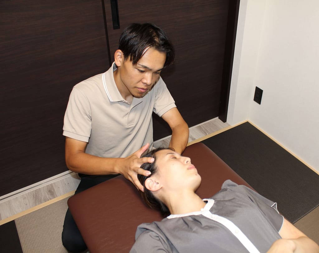 女性従業員の頭皮マッサージをする院長の写真